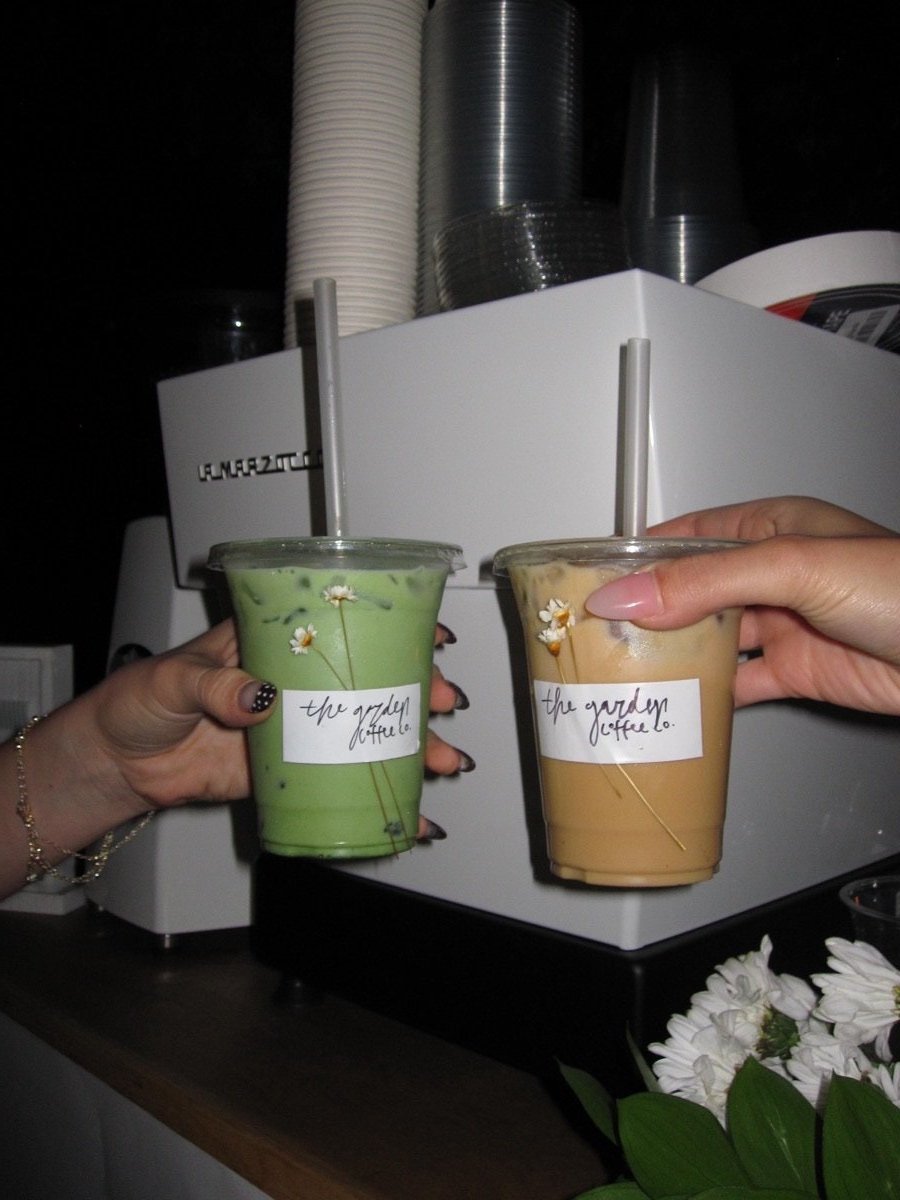 Specialty drinks in branded cups with dried flower garnish
