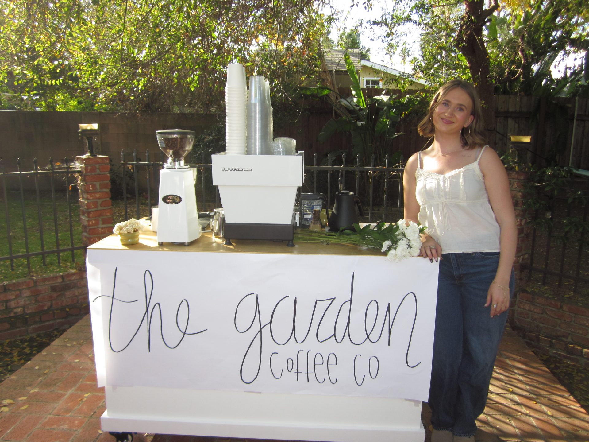 Barista standing behind The Garden Coffee Co. mobile coffee cart at an outdoor event in Los Angeles